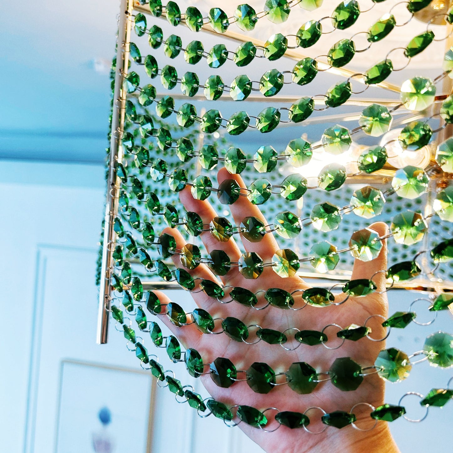Green beaded curtain held by a hand