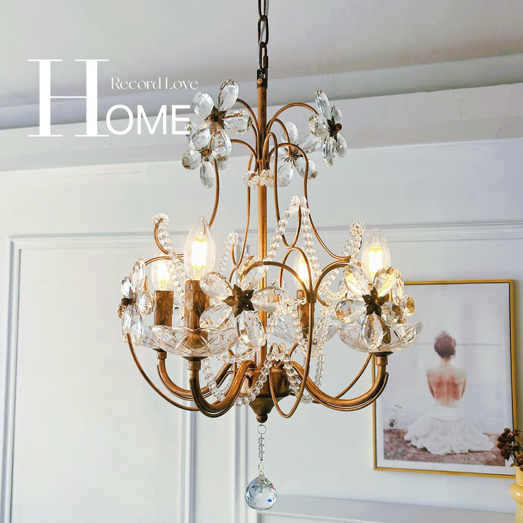 Decorative chandelier hanging in a room with a framed picture and vase.