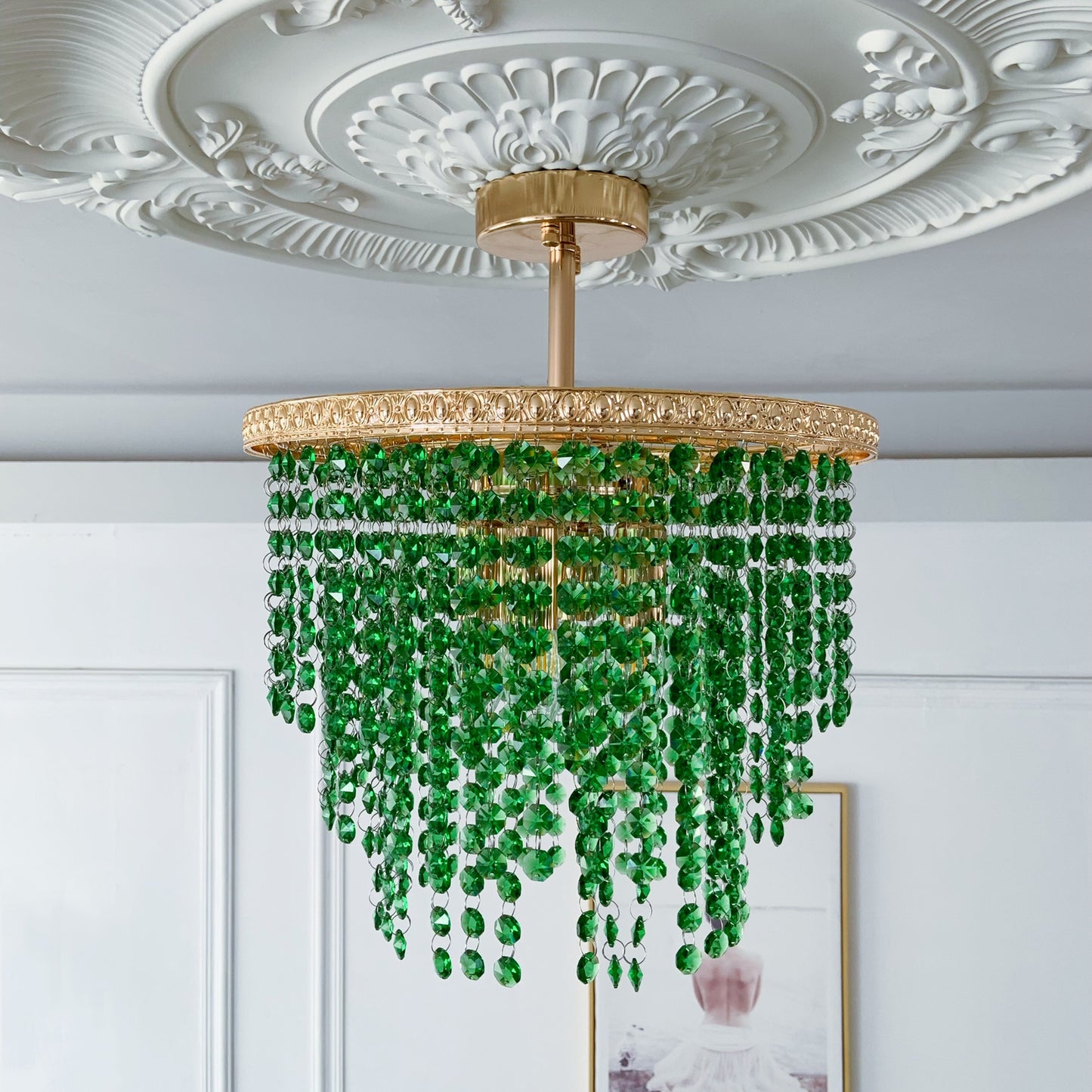 Green beaded chandelier hanging from a decorative ceiling