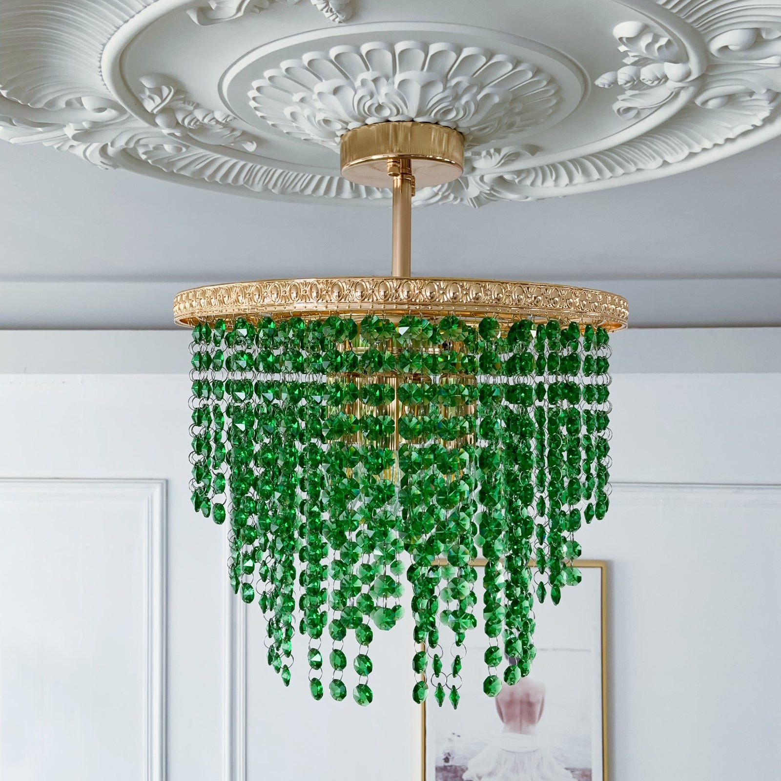 Green beaded chandelier hanging from a decorative ceiling