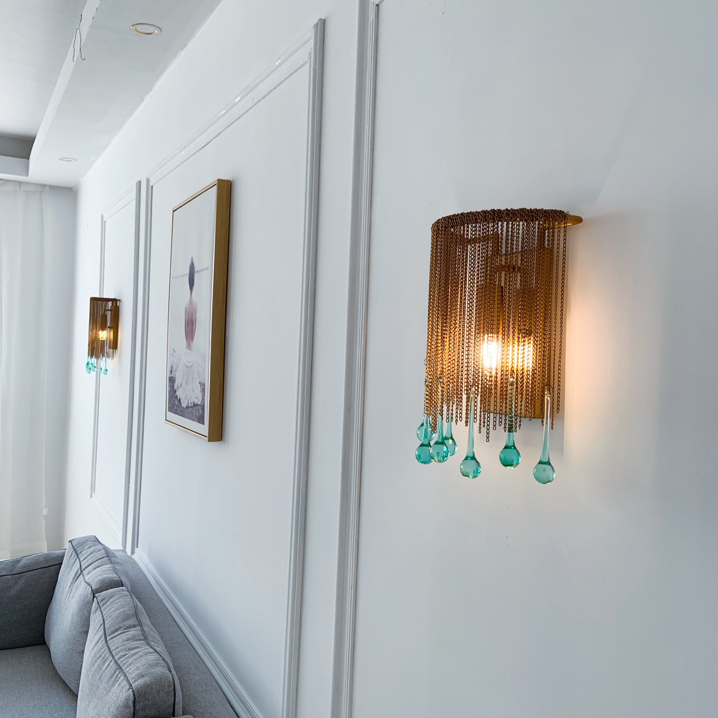 Vintage brass wall light with cascading chain and glass crystal creating elegant lighting