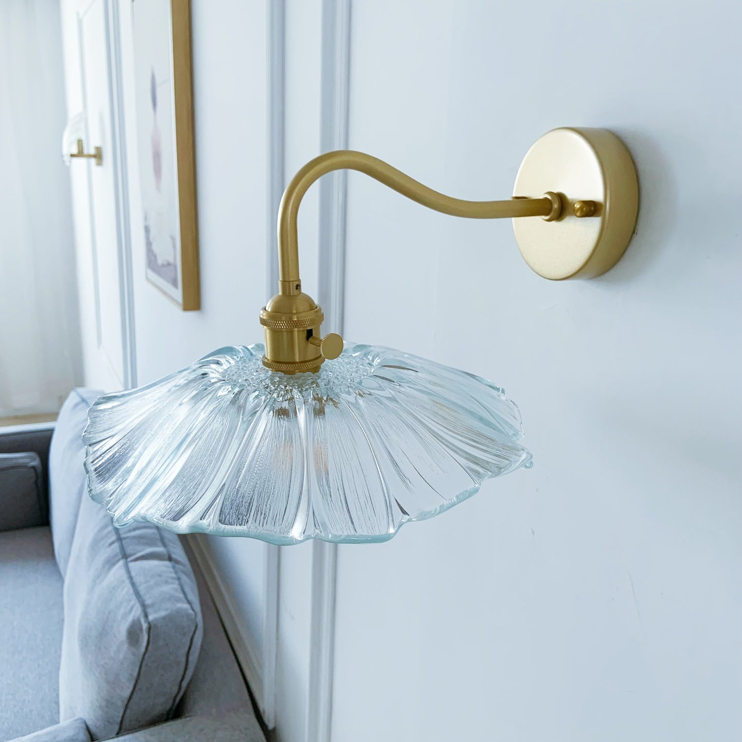 Clear glass wall light with brass finish creating bright ambient lighting in hallway