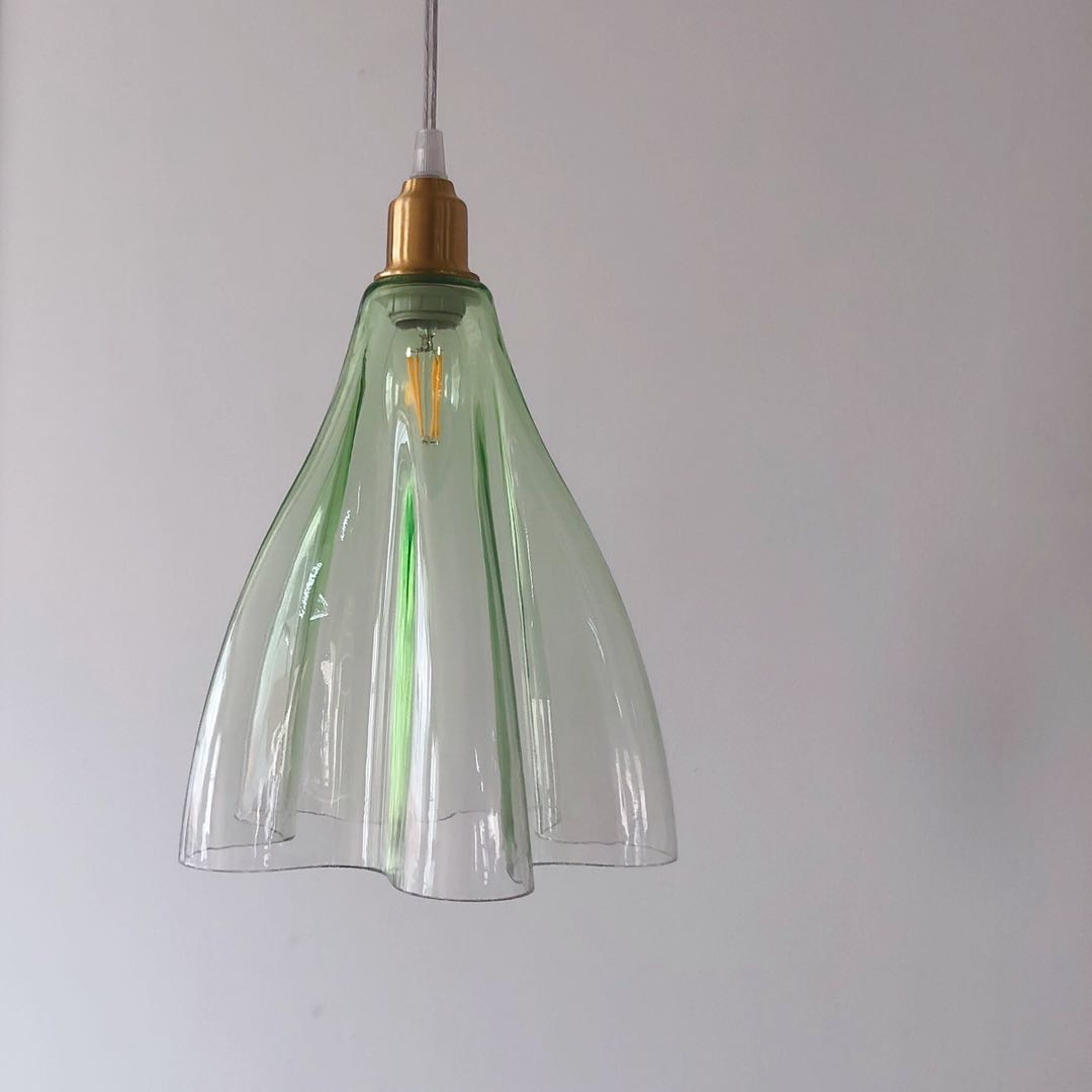 Green ruffled glass pendant with brass finish creating ambient lighting in dining nook