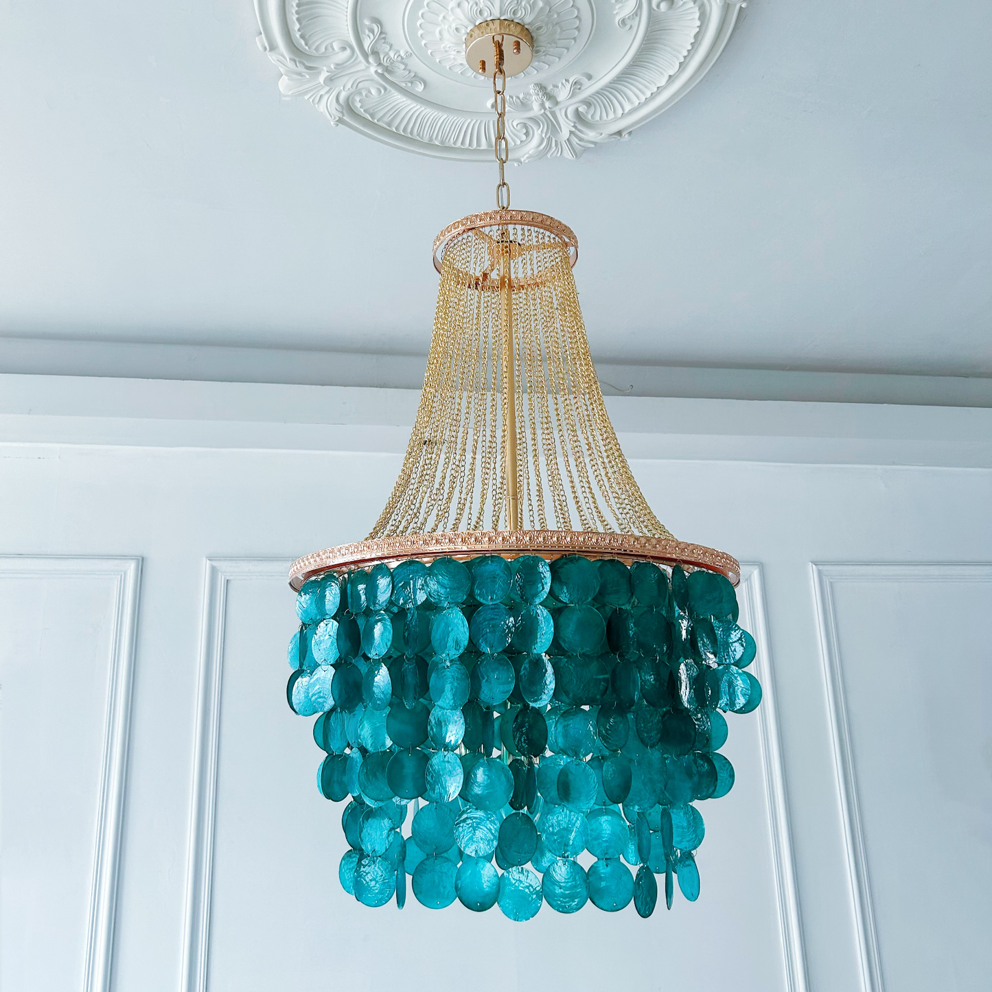 Mother of pearl chandelier close up showing handcrafted blue shell details and chain design