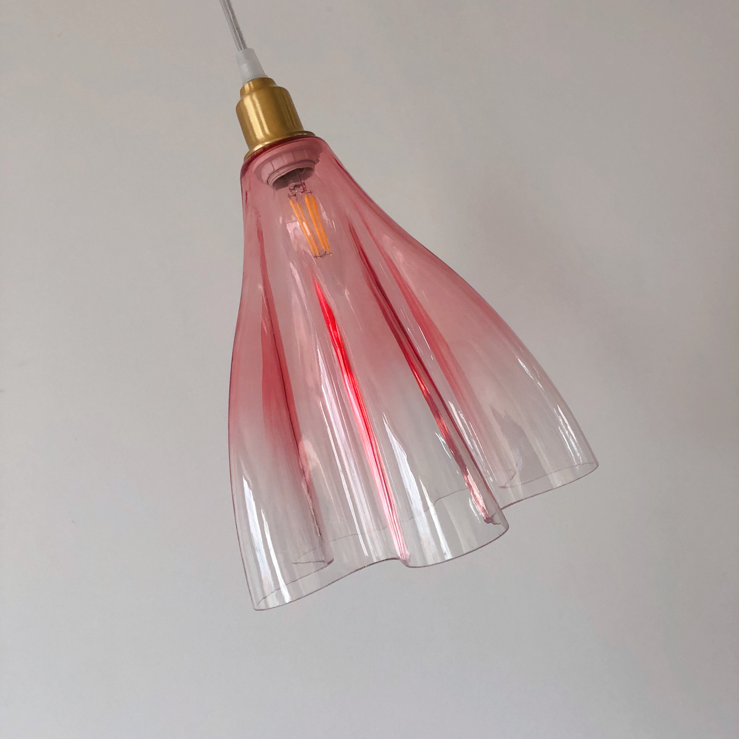 Pink gradient ruffled pendant creating warm romantic lighting in feminine bedroom space