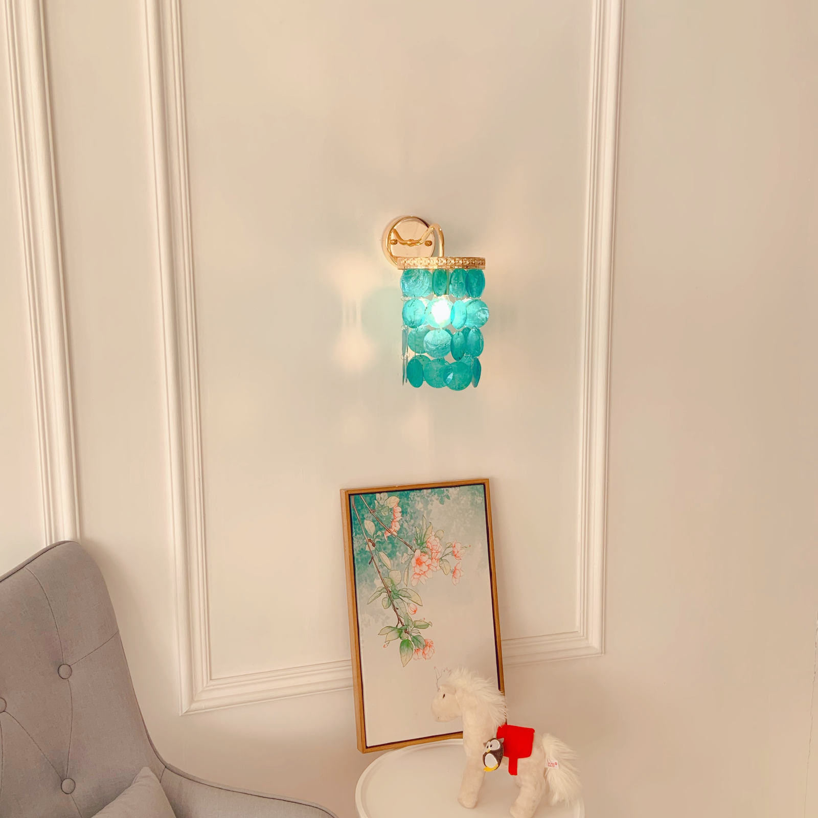 Beach house wall sconce with blue shells creating soft ambient lighting in coastal decor