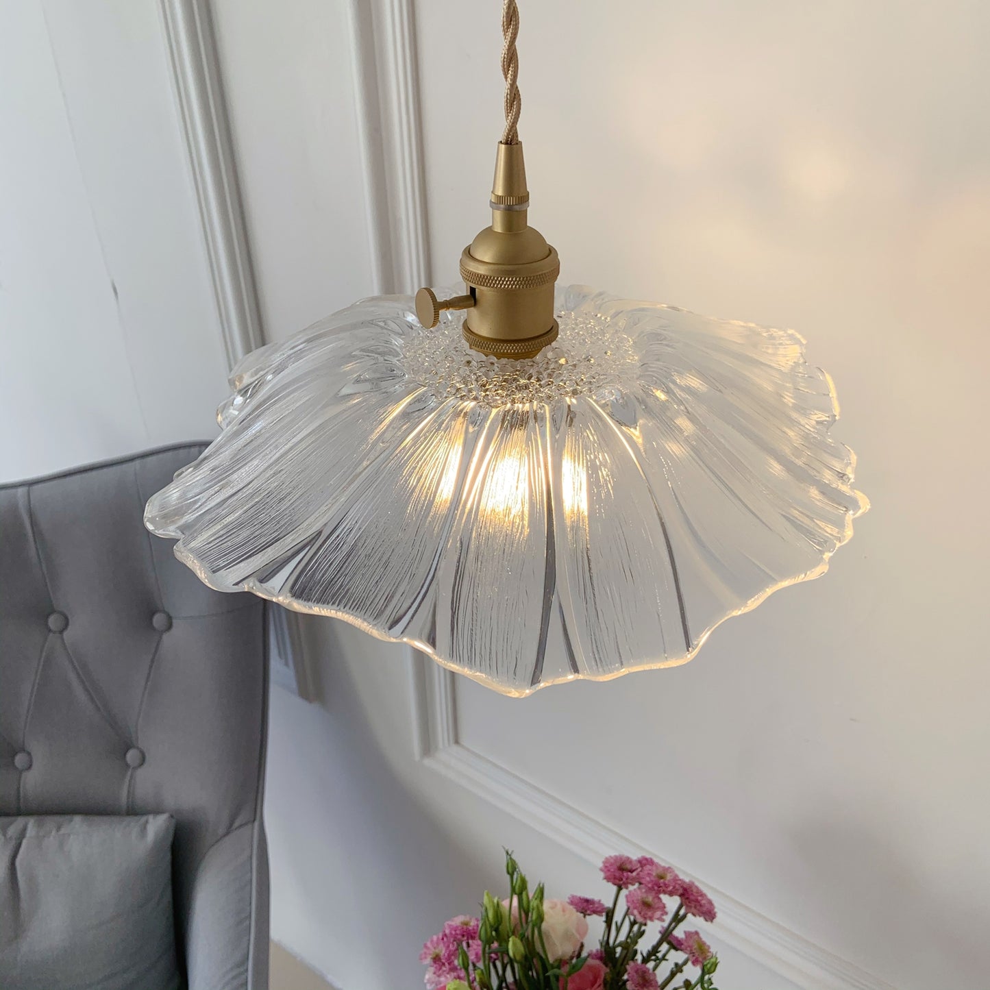 Small glass hanging light close up showing brass finish and transparent glass shade