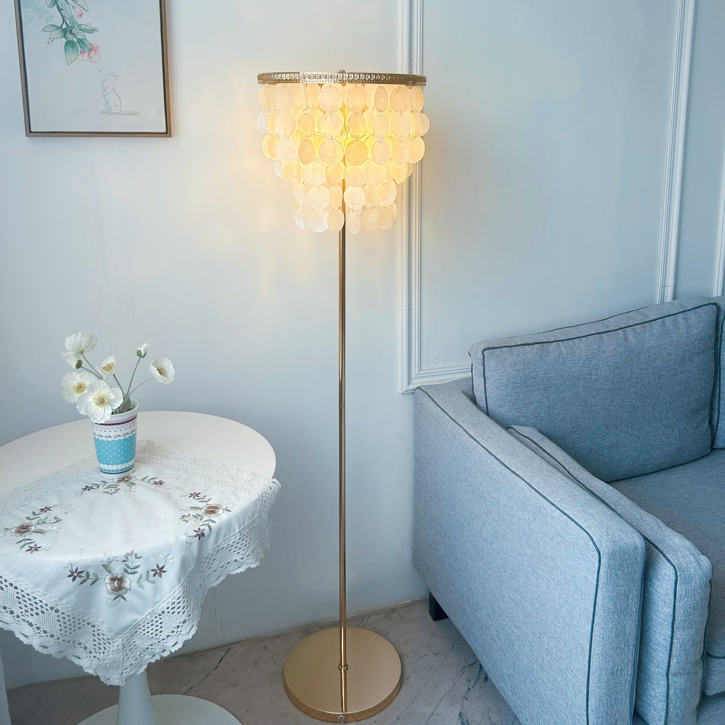 Decorative floor lamp in a living room setting with a sofa and small table.