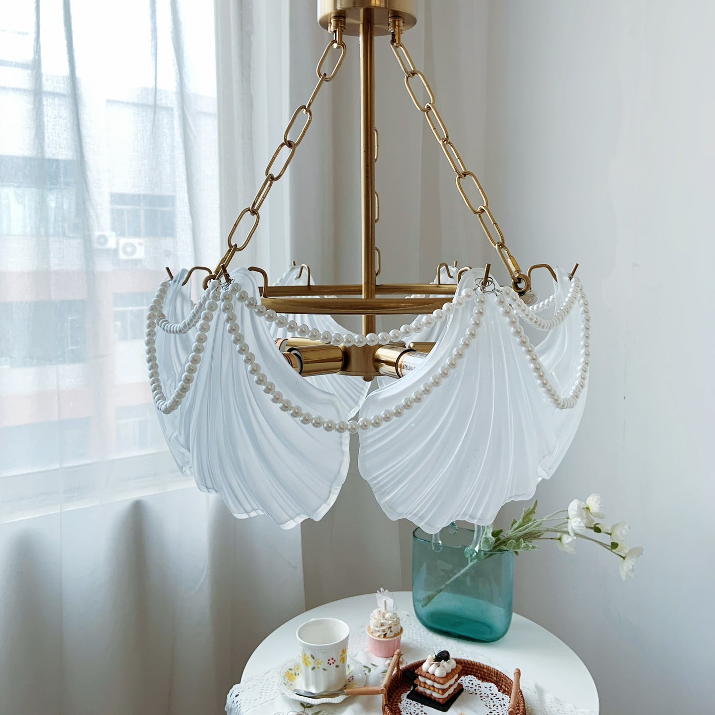 Decorative chandelier with white fabric shades in a room with light curtains.