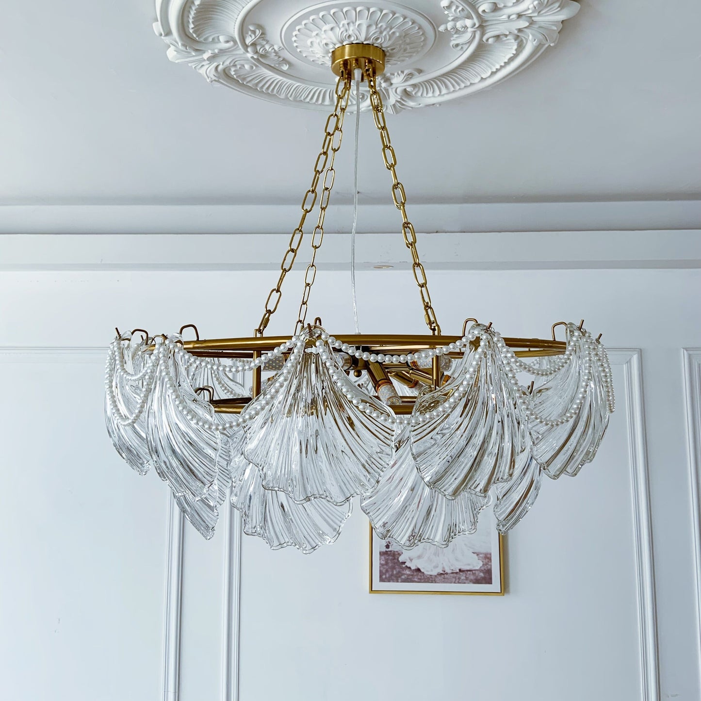 Chandelier with gold frame and clear glass elements hanging from a decorative ceiling.