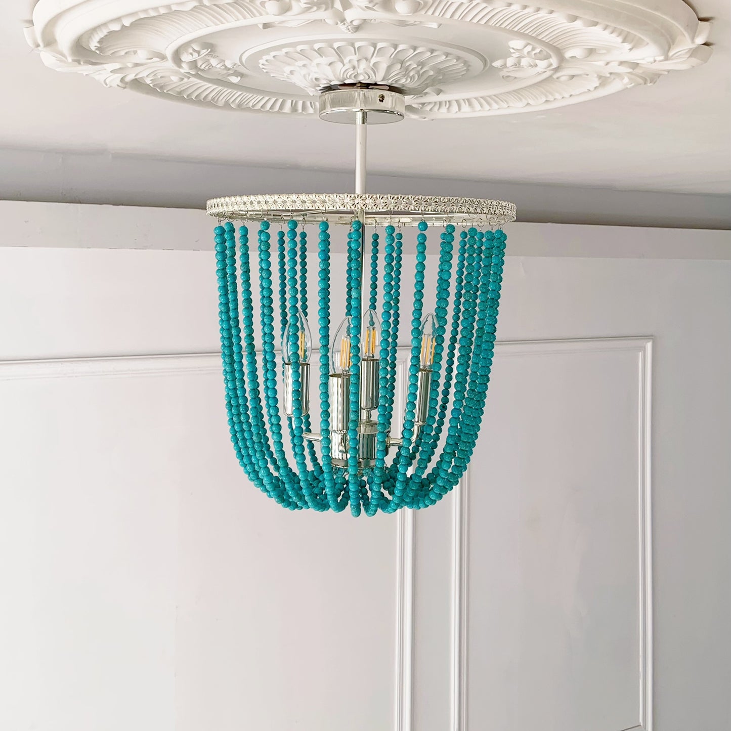 Turquoise beaded chandelier hanging from a decorative ceiling medallion.