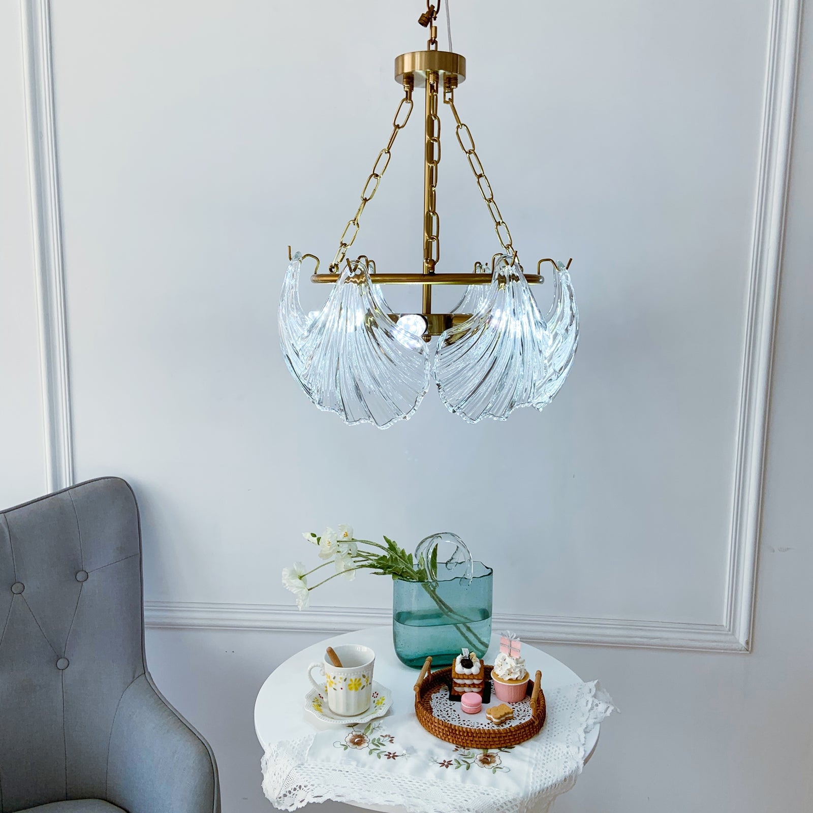 Chandelier hanging above a table with decorative items against a white wall.