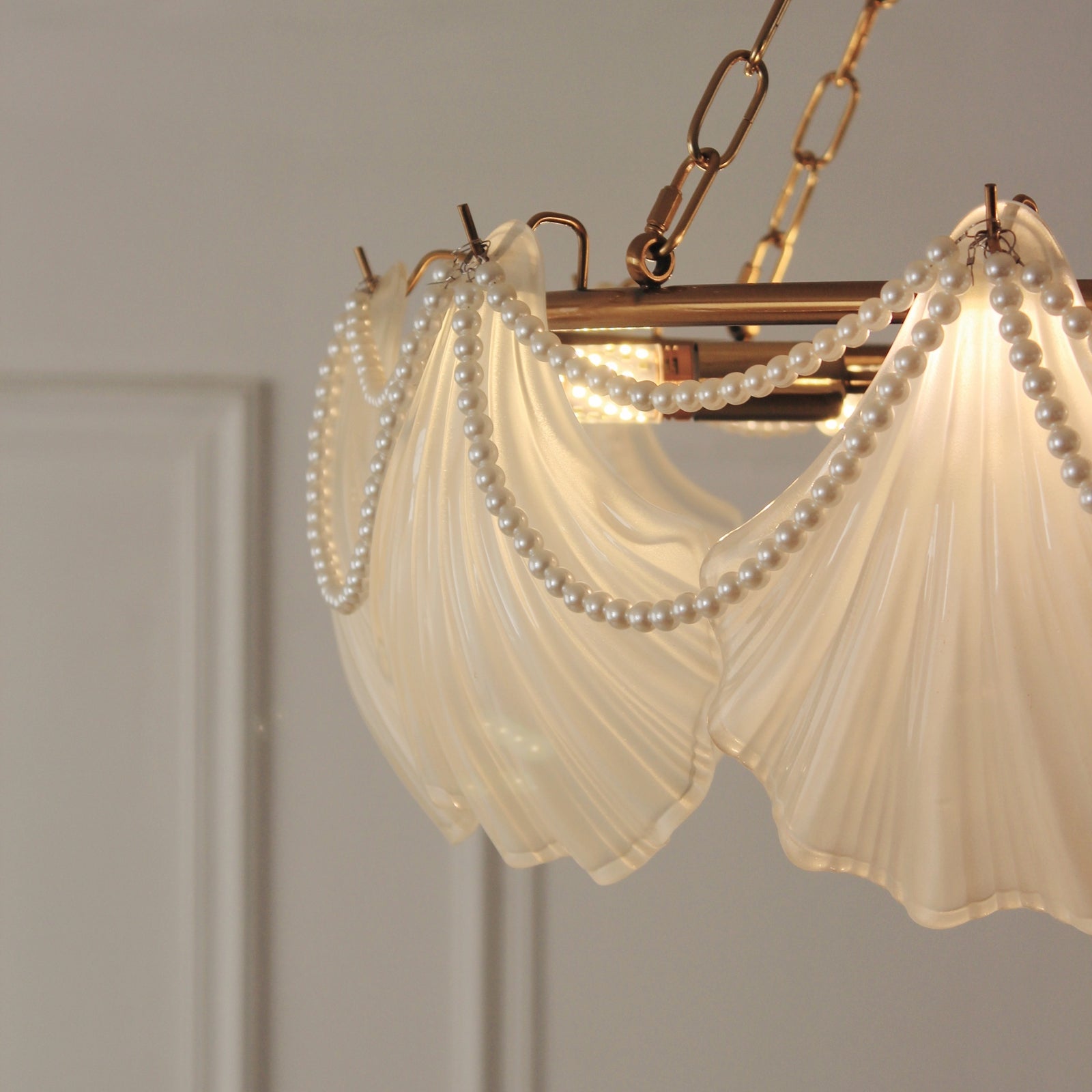 Chandelier with pleated glass and pearl strands against a neutral background