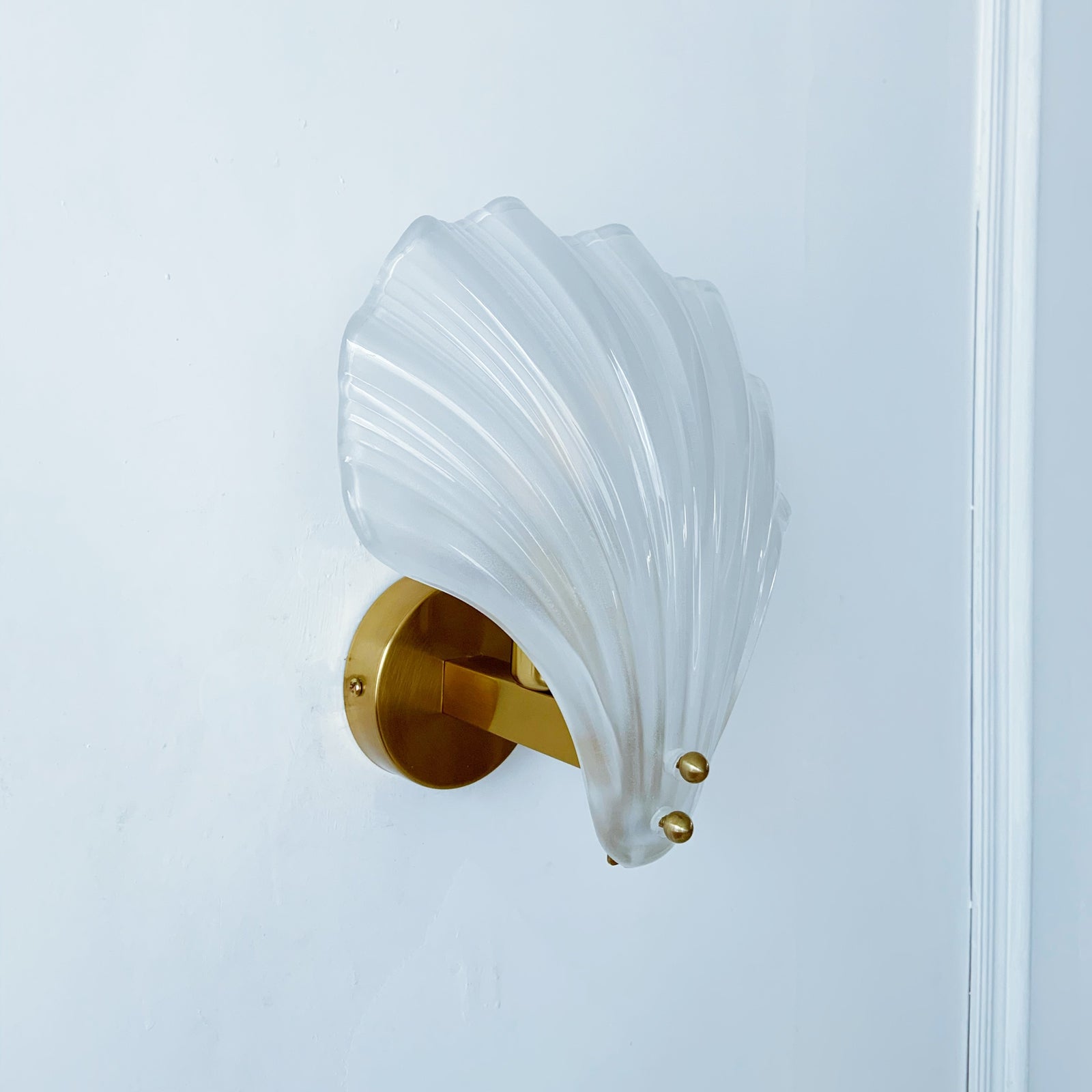 Decorative wall sconce with shell-like design and gold accents on a white background