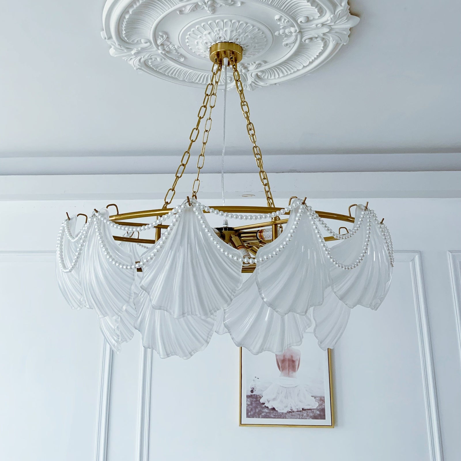 Glass Chandelier with white drapery and gold frame hanging in a room with decorative ceiling