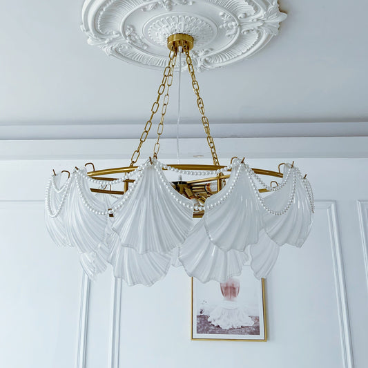 Glass Chandelier with white drapery and gold frame hanging in a room with decorative ceiling