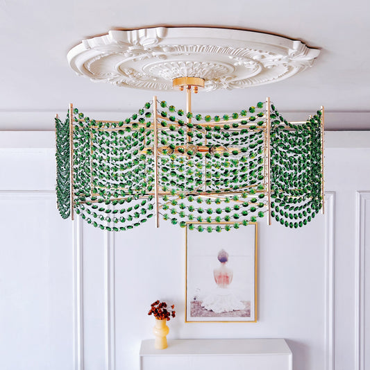 Decorative chandelier with green beads hanging from a white ceiling