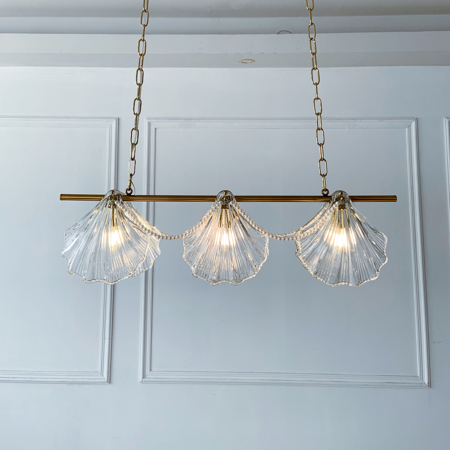 Chandelier with shell-shaped glass lights on a white paneled wall