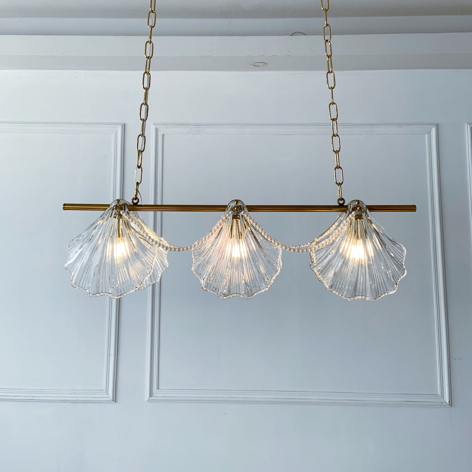 Chandelier with shell-shaped glass lights on a white paneled wall