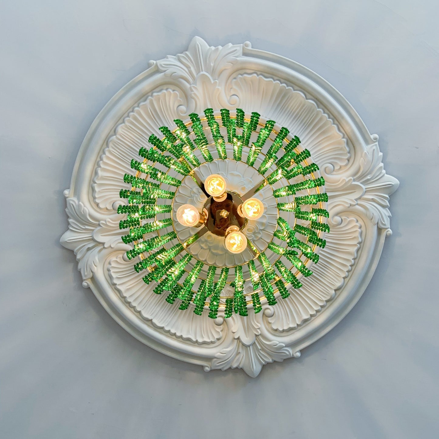 Decorative ceiling light fixture with green beaded design on a white ceiling