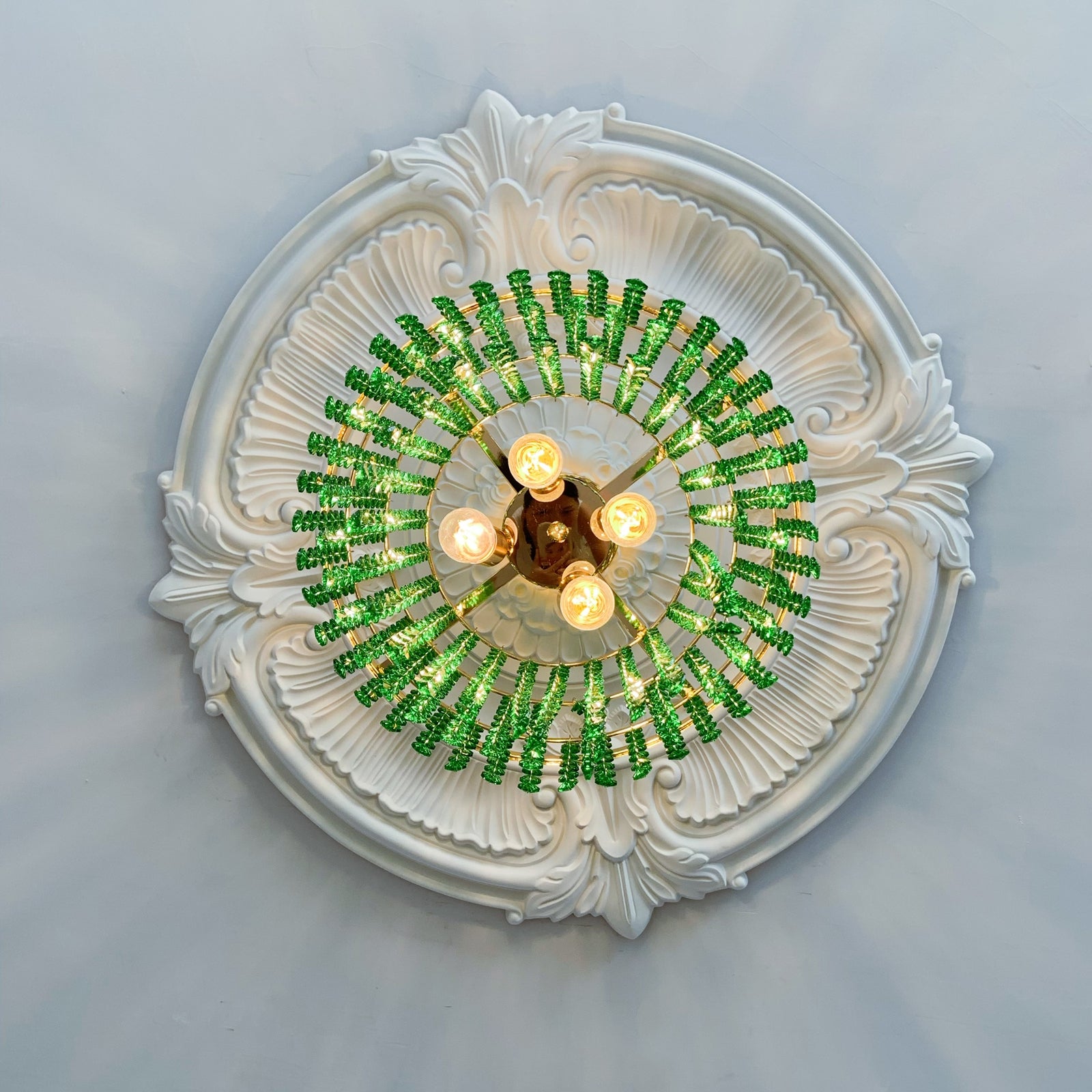 Decorative ceiling light fixture with green beaded design on a white ceiling