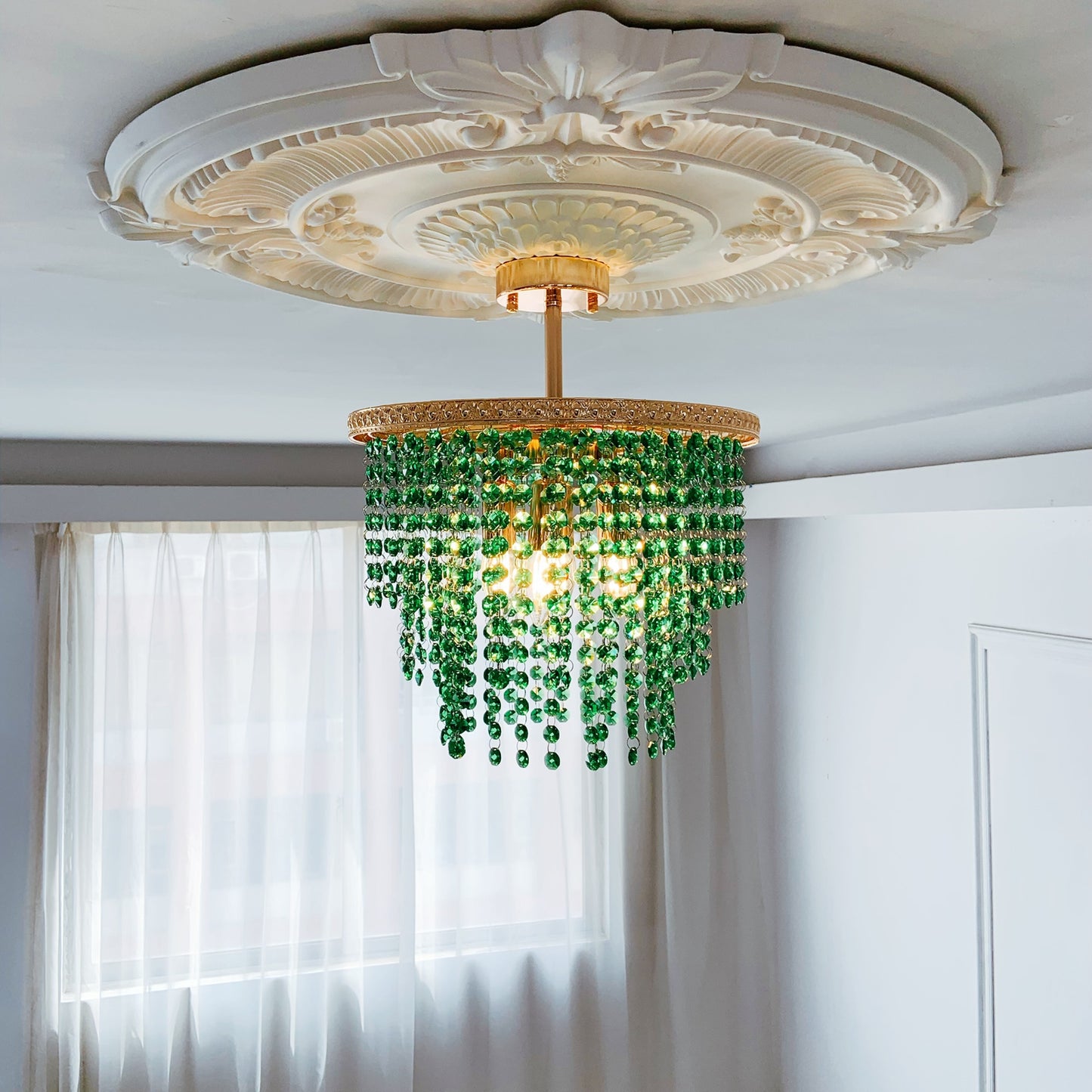 Green chandelier hanging from a decorative ceiling 