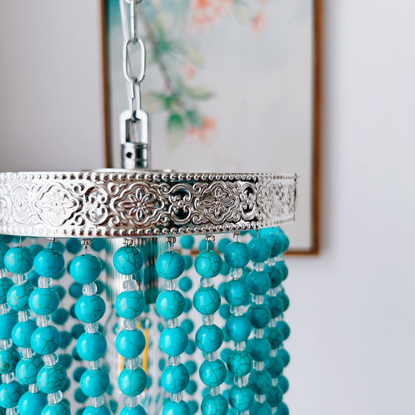 Turquoise beaded chandelier with silver fixture against a neutral background