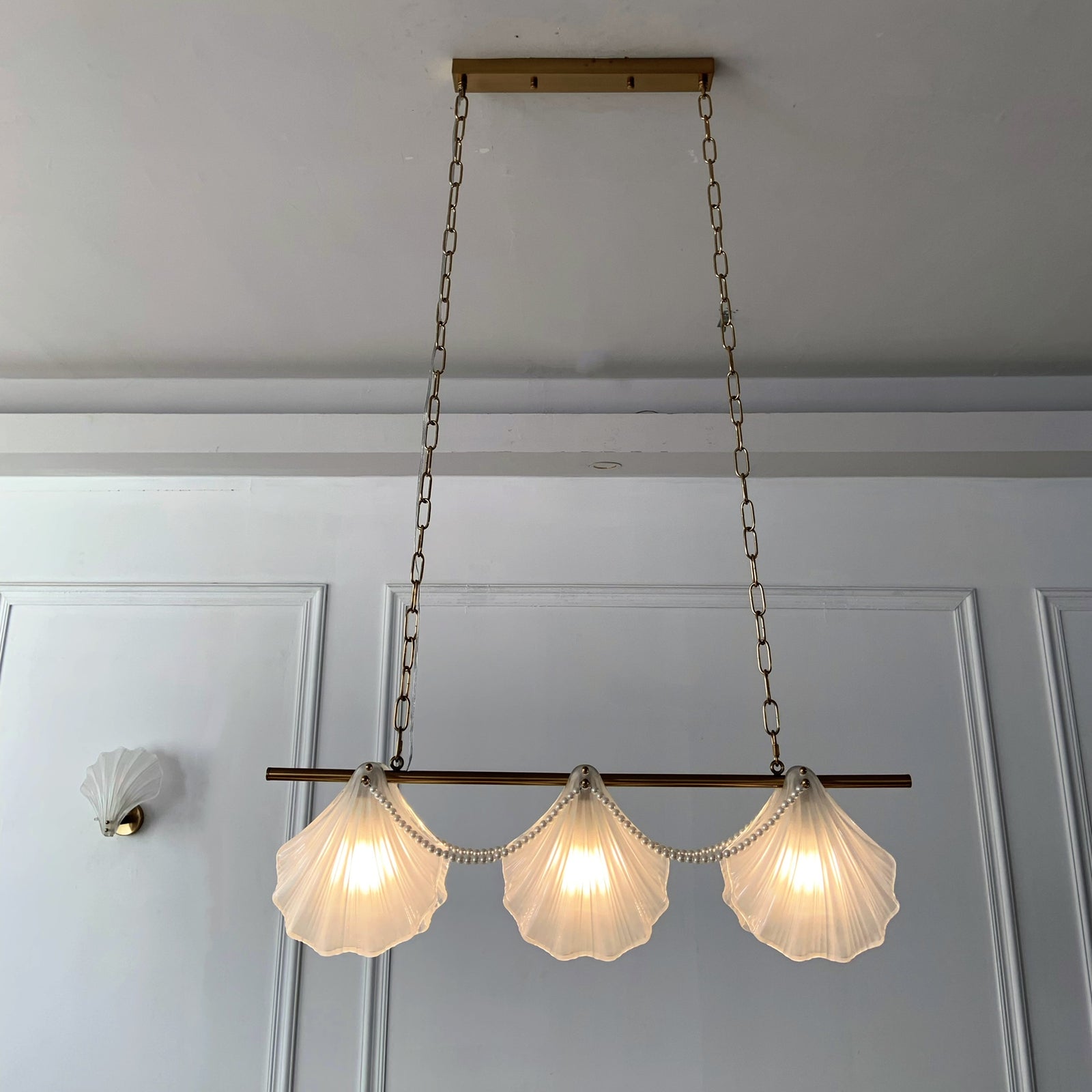 Ceiling light fixture with shell-shaped lampshades in a room with white walls and a door.