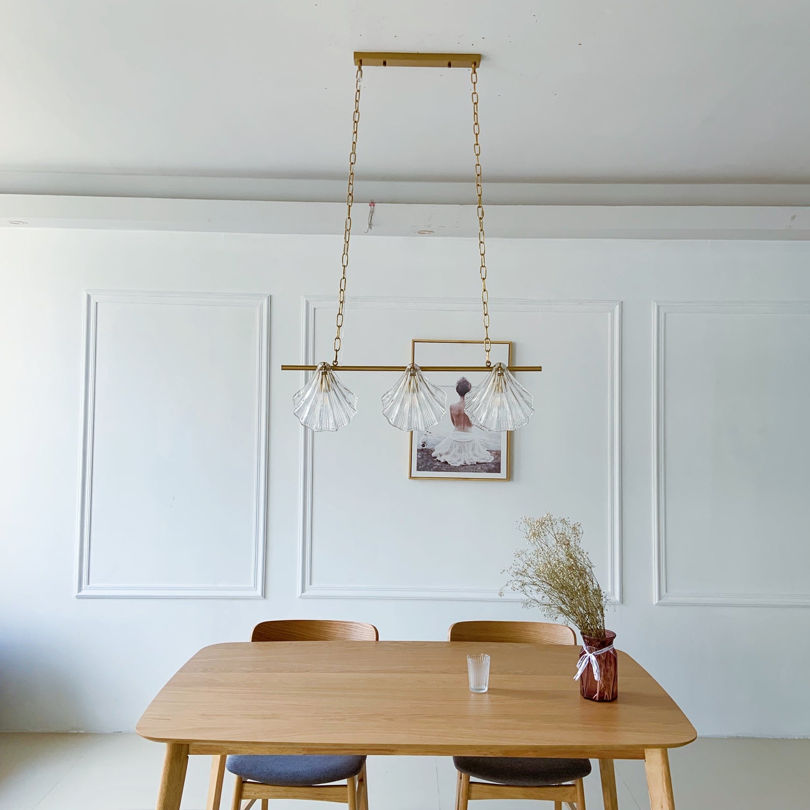Dining room with a wooden table, chairs, and a hanging gold light fixture.